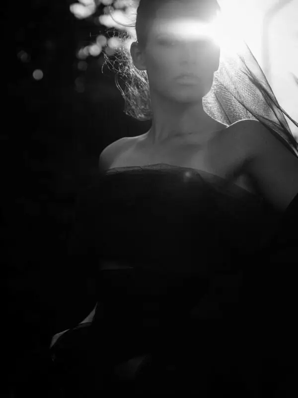 Black and white fine art portrait of a sunlit seduction, woman bathed in soft light and shadow, evoking warmth, intimacy, and poetic allure